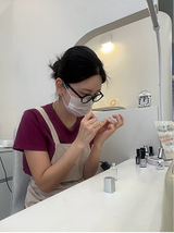Nail artist working at a desk wearing a mask